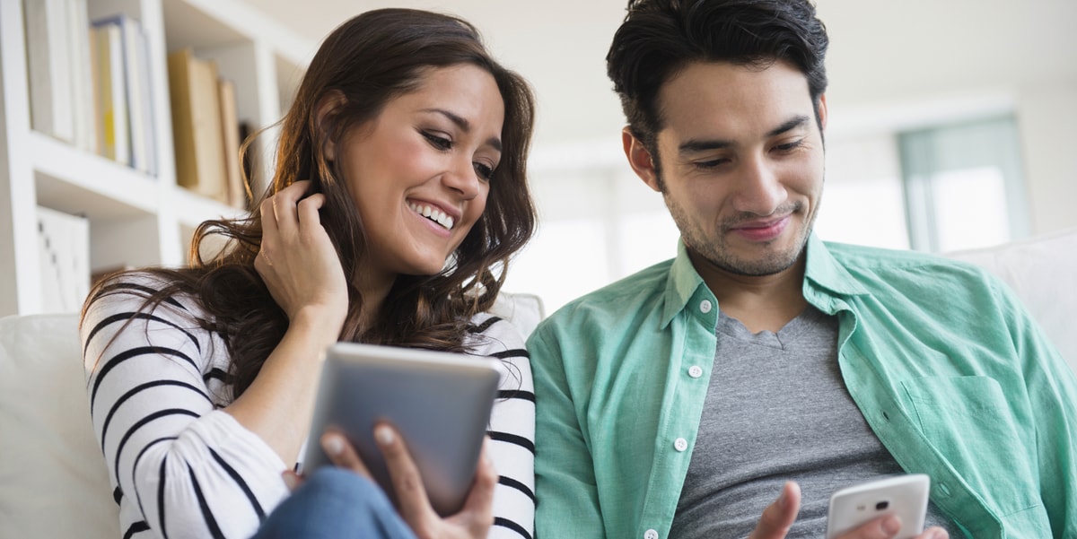 two people sitting together and looking at an electronic device