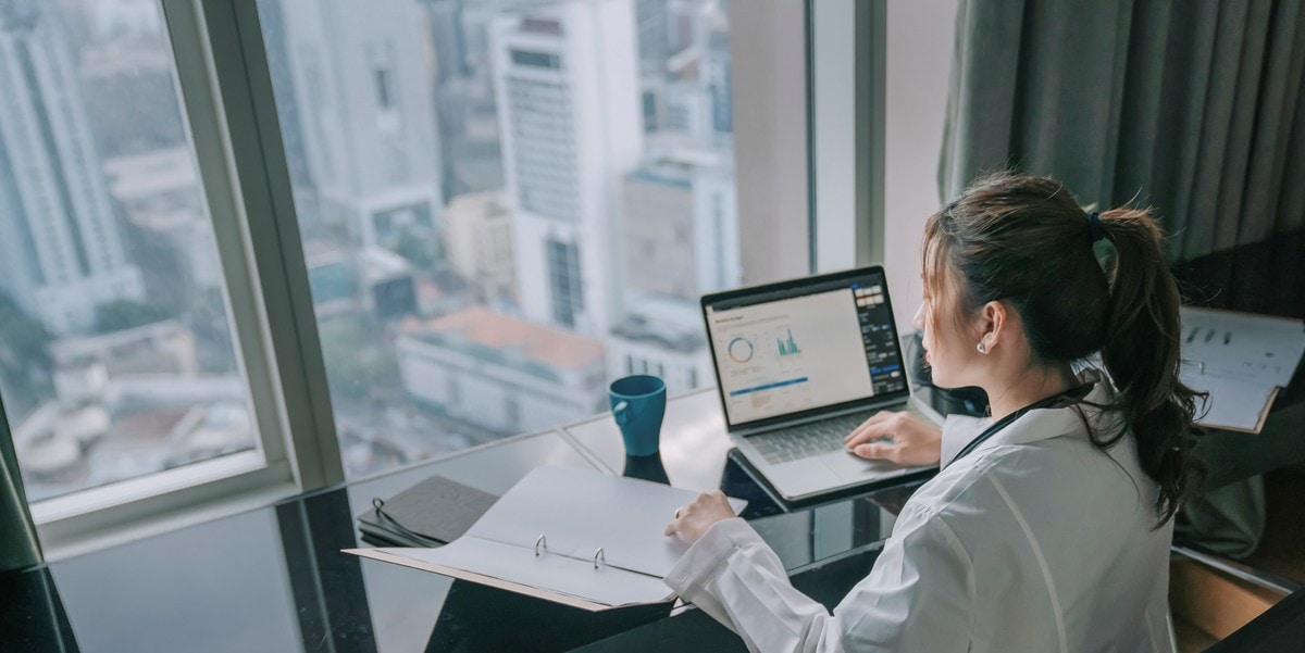 woman working in office, laptop and documents in front of her