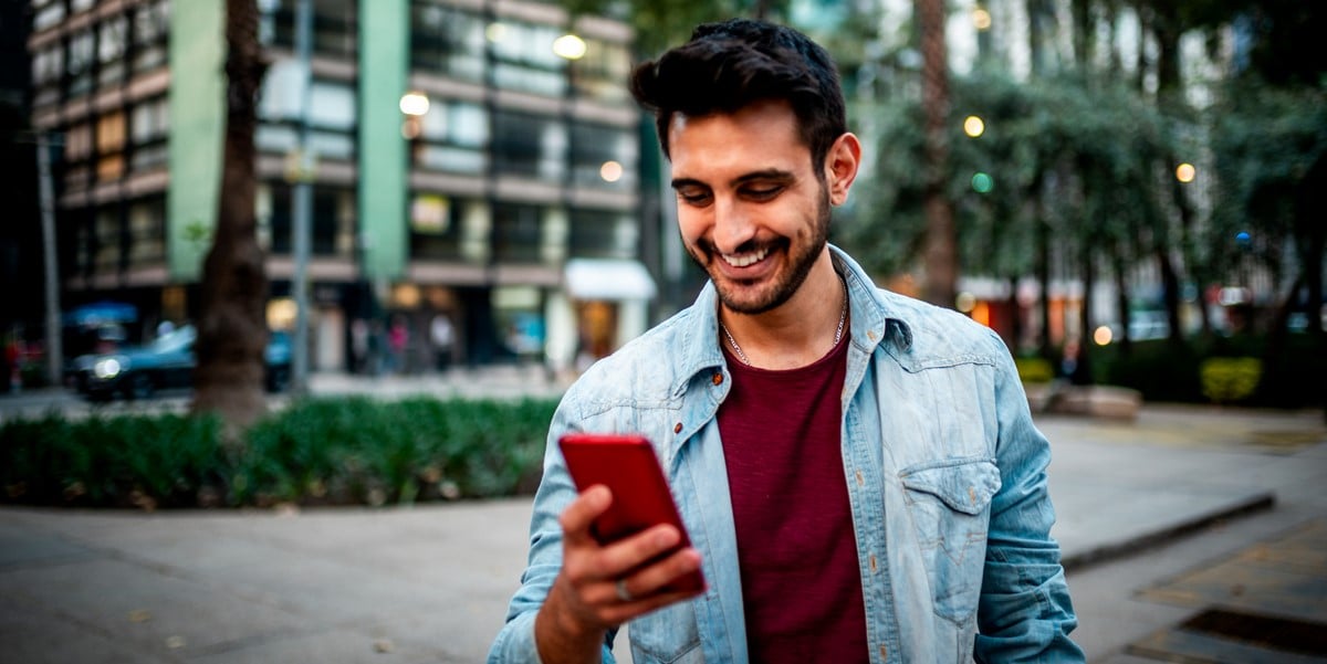 hombre parado afuera con celular, ciudad